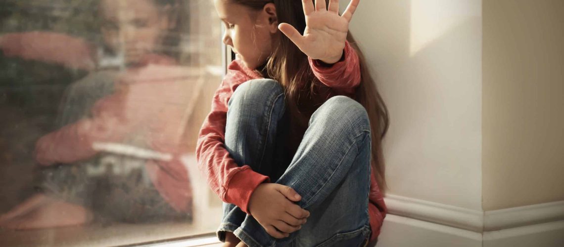 Helpless little girl near window. Abuse of children concept